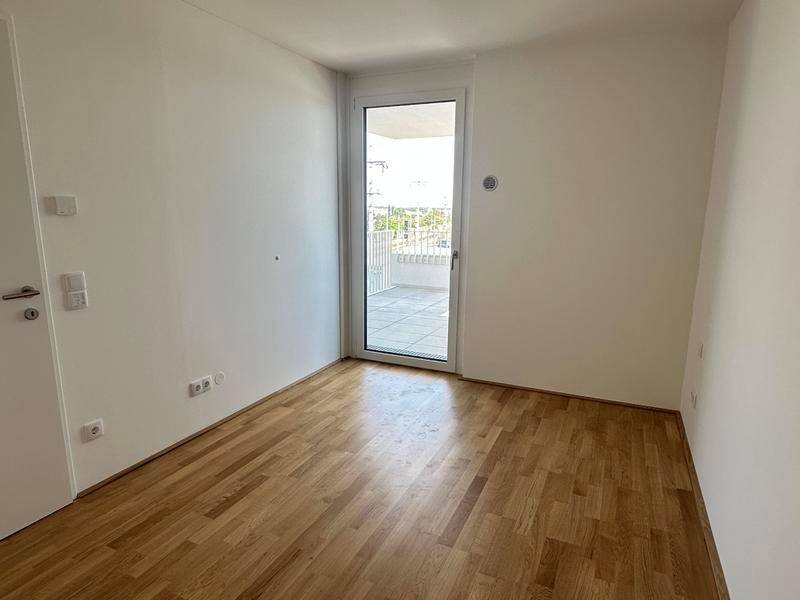Helles Schlafzimmer mit Parkettboden und direktem Zugang zu einem Außenbereich.