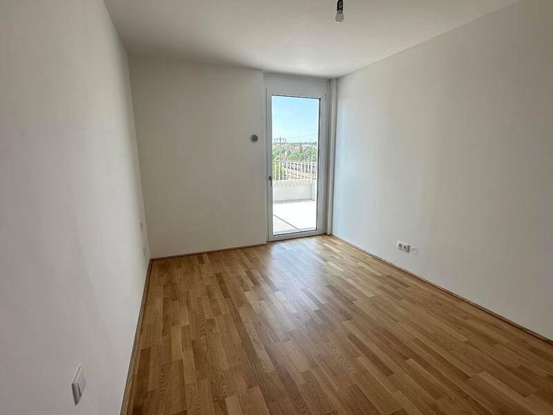 Helles Schlafzimmer mit Eichenparkettboden und direktem Zugang zu einem Balkon.