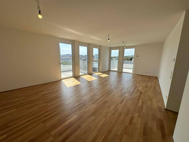 Heller Wohnraum mit Parkettboden und Zugang zu einer großen Terrasse.