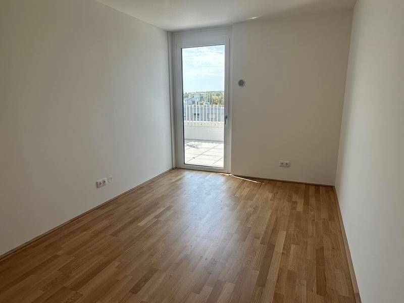 Schlafzimmer mit Parkettboden und direktem Zugang zur Terrasse.