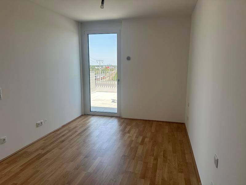 Helles Schlafzimmer mit Parkettboden und direktem Zugang zur Terrasse.
