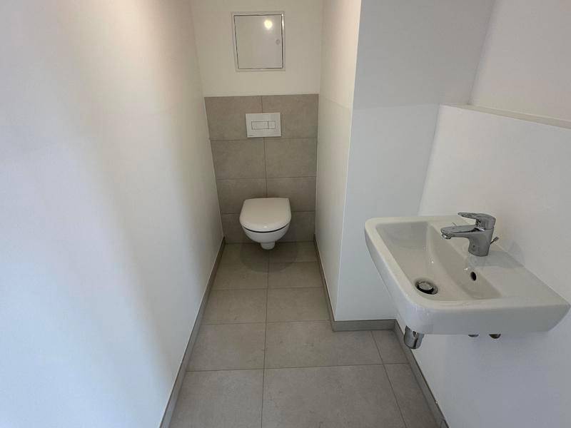 Separates Gäste-WC mit wandhängendem WC und kleinem Waschbecken.