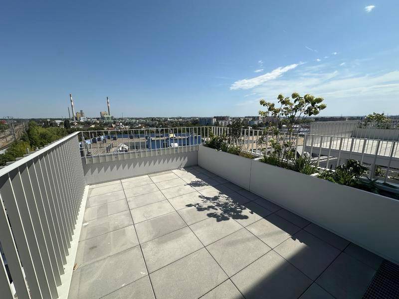 Geräumige Dachterrasse mit Fliesenboden, Pflanzenkübeln und weitem Stadtblick.