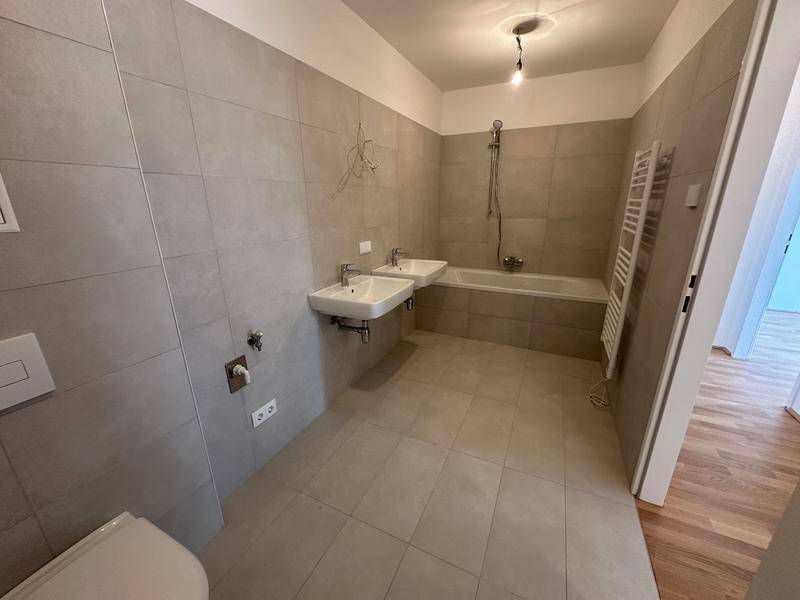 Modernes Badezimmer mit Doppelwaschbecken, Badewanne und beheiztem Handtuchhalter.