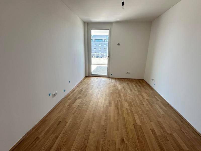 Unmöbliertes Schlafzimmer mit Parkettboden und Zugang zu einem Außenbereich, hell und freundlich.