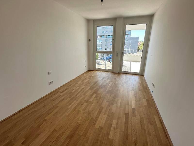 Helles Schlafzimmer mit Parkettboden und großen Fenstern, die viel Tageslicht hereinlassen.