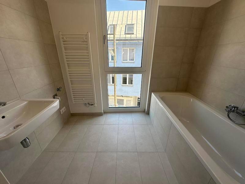 Modernes Badezimmer mit Badewanne, Waschbecken und beheiztem Handtuchhalter.