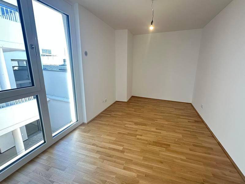 Geräumiges Schlafzimmer mit Holzparkettboden und großen Fenstern für viel Licht.