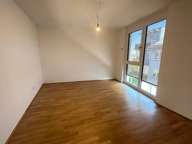 Helles Schlafzimmer mit Holzparkettboden und Blick auf die umliegenden Gebäude.