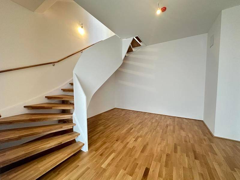 Elegante Holztreppe mit weißem Geländer, die zu den oberen Etagen führt.