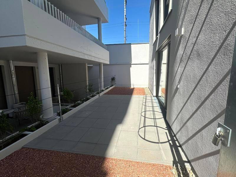 Gepflegter Außenbereich mit grauen Fliesen und Kies, ideal für eine Terrasse.