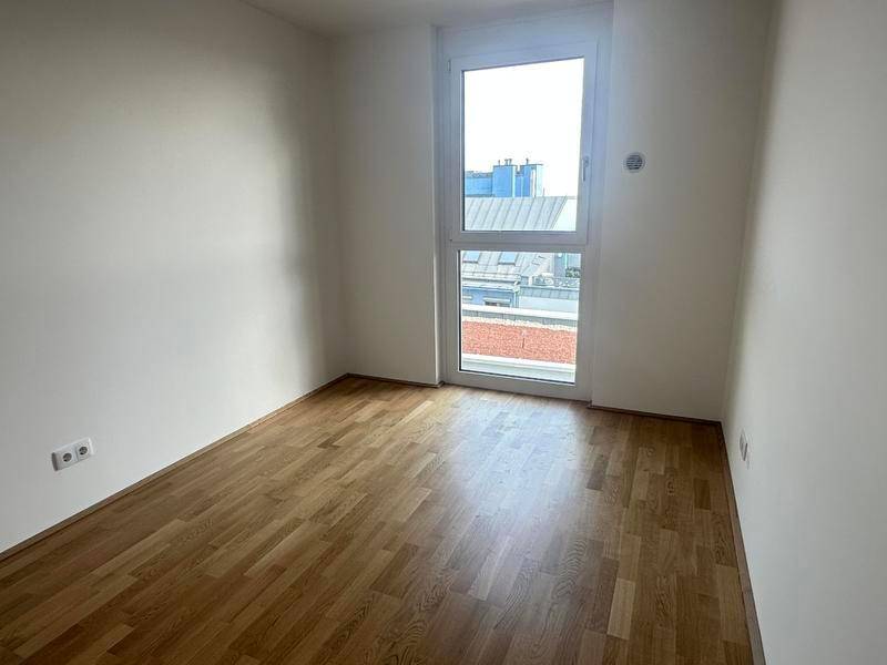 Kleiner, heller Raum mit Holzboden und einem Fenster, ideal als Schlaf- oder Arbeitszimmer.