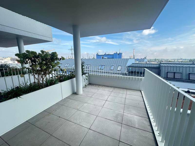 Geräumige Terrasse mit Fliesenboden und Blick auf die umliegenden Gebäude und Dächer.