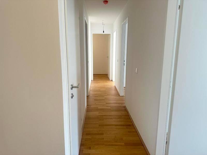 Langer, heller Flur mit Holzboden, der verschiedene Räume der Wohnung verbindet.