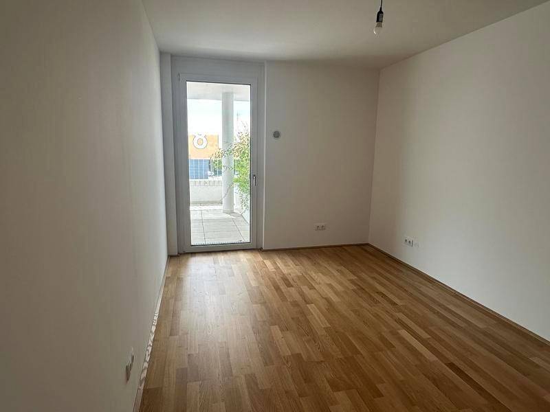 Lichtdurchfluteter Raum mit Holzboden und direktem Zugang zu einem privaten Balkon.