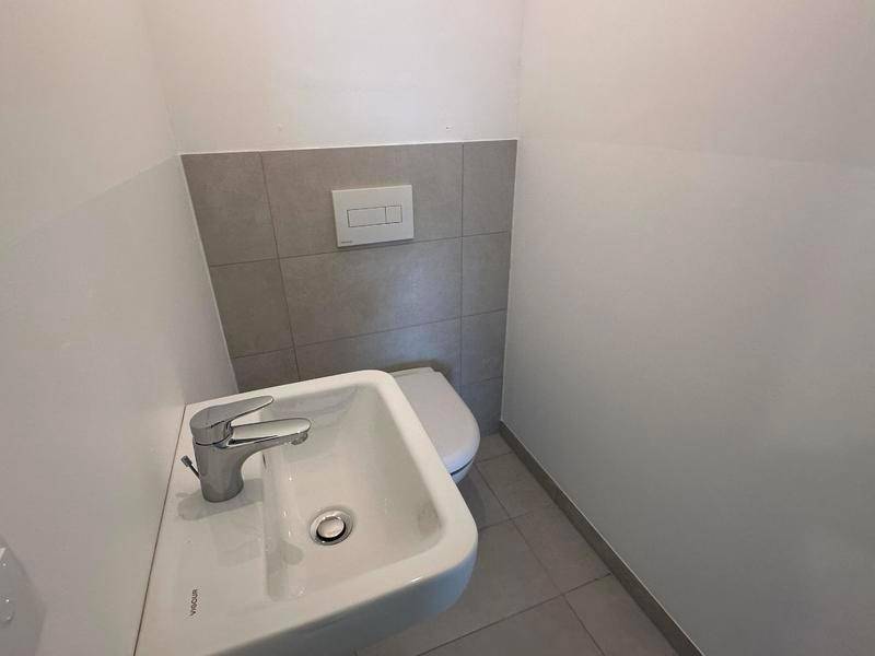 Kompaktes Gäste-WC mit modernem Waschbecken und wandhängender Toilette, hell gefliest.