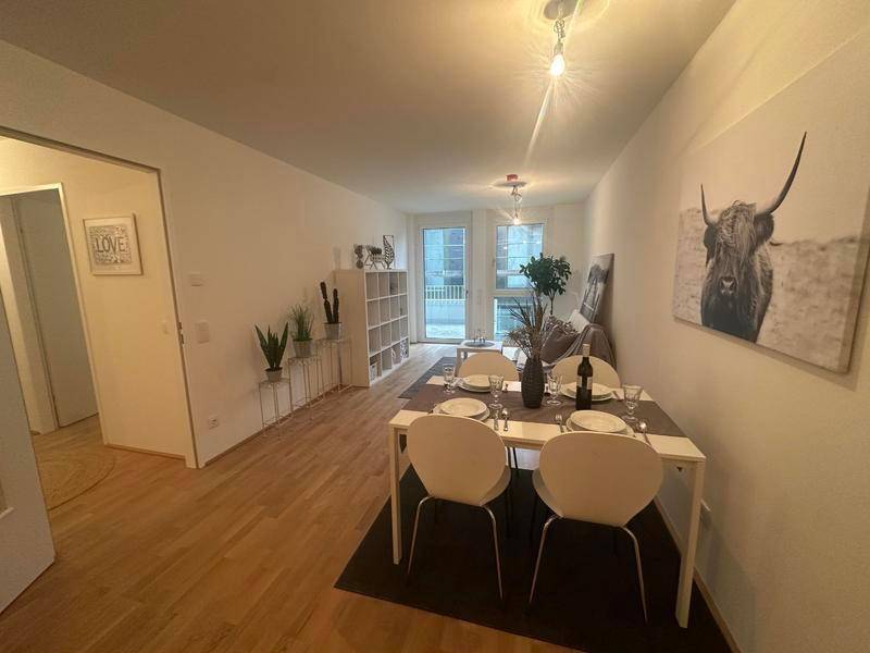 Geräumiger Wohn- und Essbereich mit Holzboden, schlichtem Esstisch und moderner Dekoration.