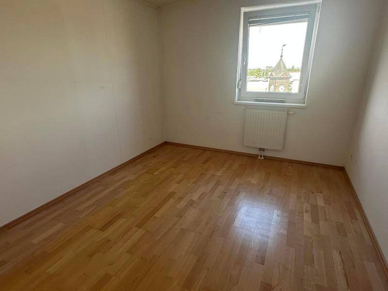 Weiteres Schlafzimmer mit Parkettboden und einem Fenster, das einen Blick auf die Umgebung bietet.