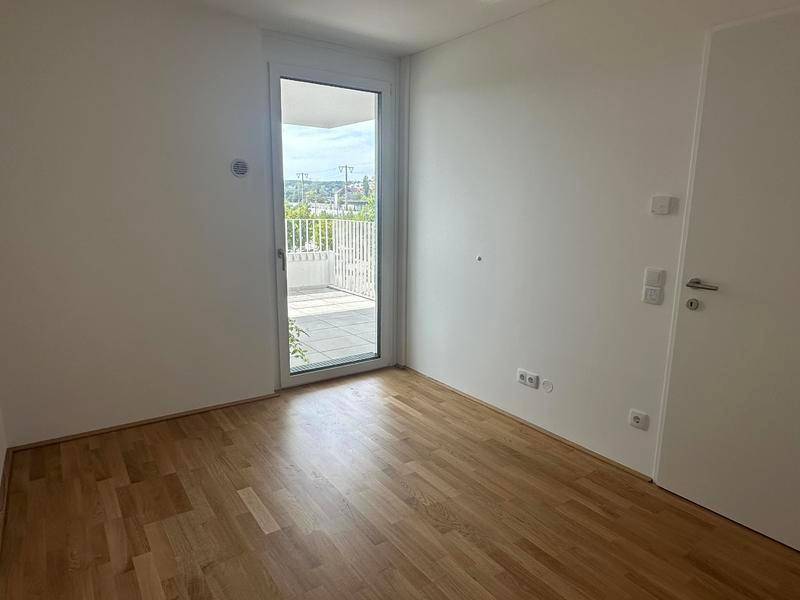 Helles Schlafzimmer mit Holzboden und direktem Zugang zu einem privaten Balkon.