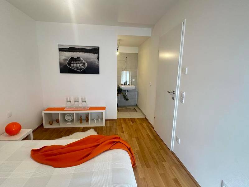 Schlafzimmer mit Holzboden und Zugang zu einem modernen Badezimmer mit Waschtisch.