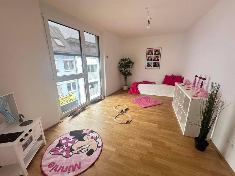 Kinderzimmer mit Holzboden, großem Fenster und verspielter Dekoration in Pink.