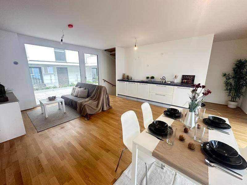 Geräumiger Wohn-Essbereich mit moderner Einrichtung, Holzboden und Zugang zur Terrasse.