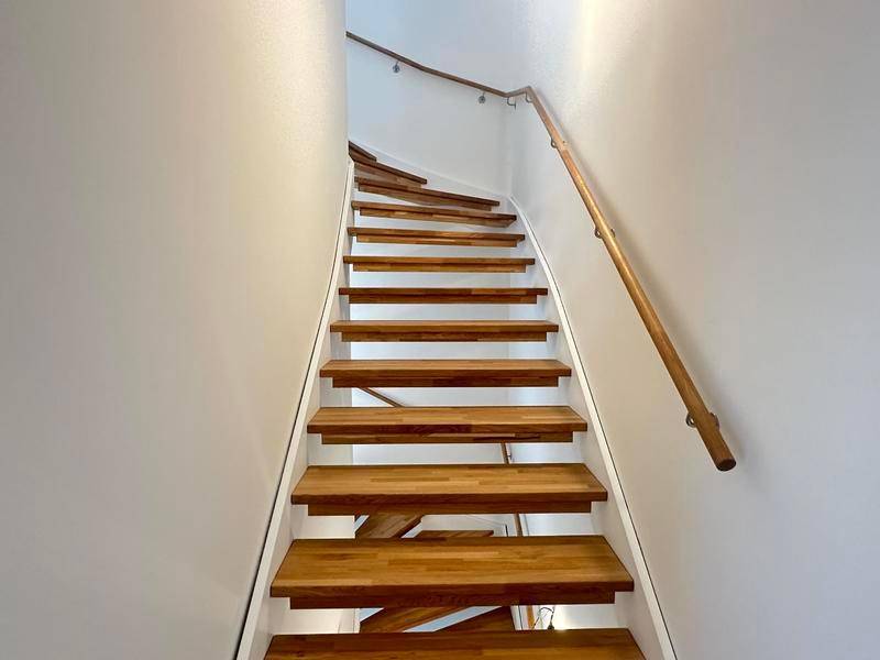 Moderne Holztreppe mit schlichtem Geländer, die die verschiedenen Ebenen verbindet.