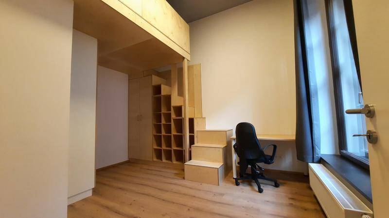 Zimmer mit Holz-Hochbettkonstruktion, integriertem Schreibtisch und Stauraum unter der Treppe.