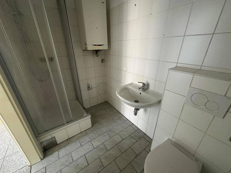 Funktionales Badezimmer mit Duschkabine, Waschbecken und WC, komplett gefliest.