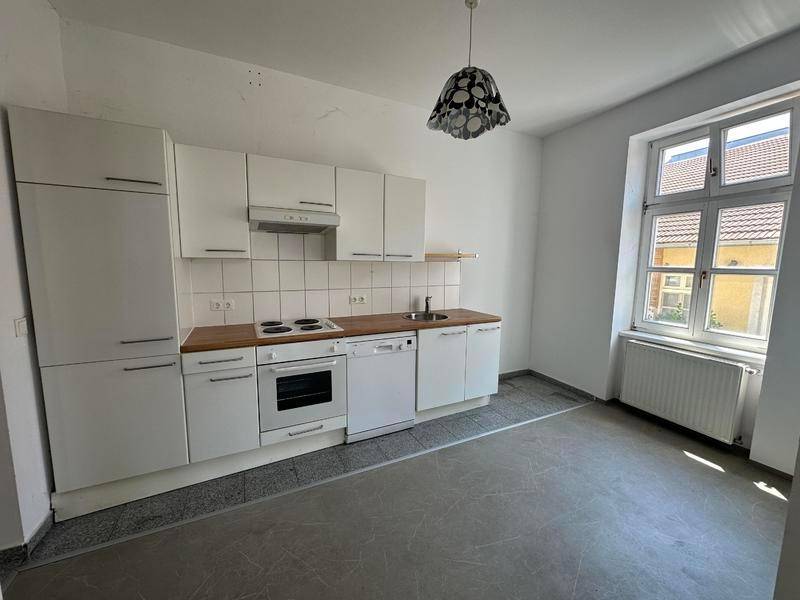 Helle Einbauküche mit weißen Fronten, Holz-Arbeitsplatte und Fliesenboden, gut erhalten.