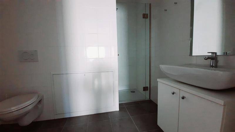 Modernes Badezimmer mit Duschkabine, wandhängendem WC und Einzelwaschbecken.