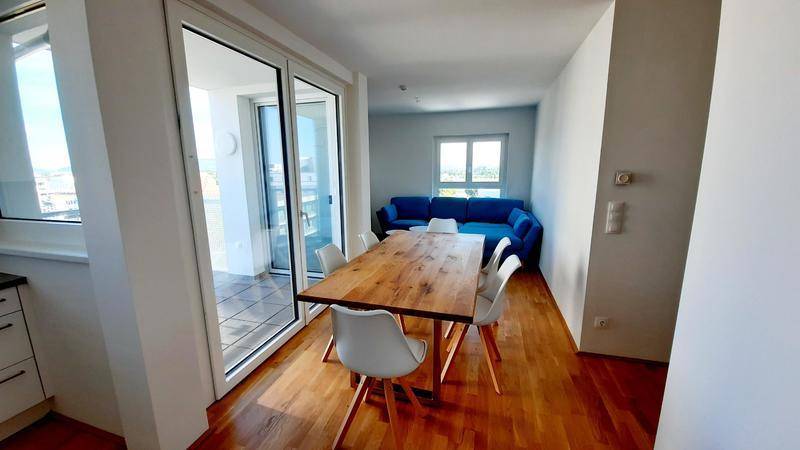 Offener Wohn-Essbereich mit Holzboden, Esstisch und Blick auf den Wohnbereich.