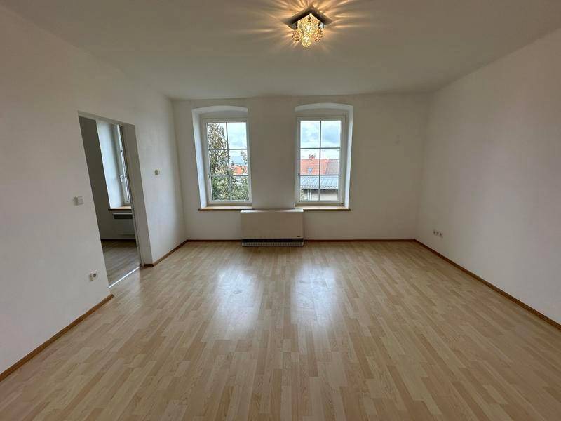 Lichtdurchfluteter Wohnraum mit Laminatboden und Blick auf die umliegenden Dächer.