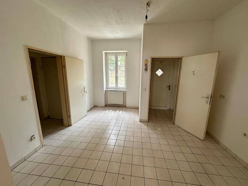 Eingangsbereich mit Fliesenboden, mehreren Türen und einem Fenster, das Licht spendet.