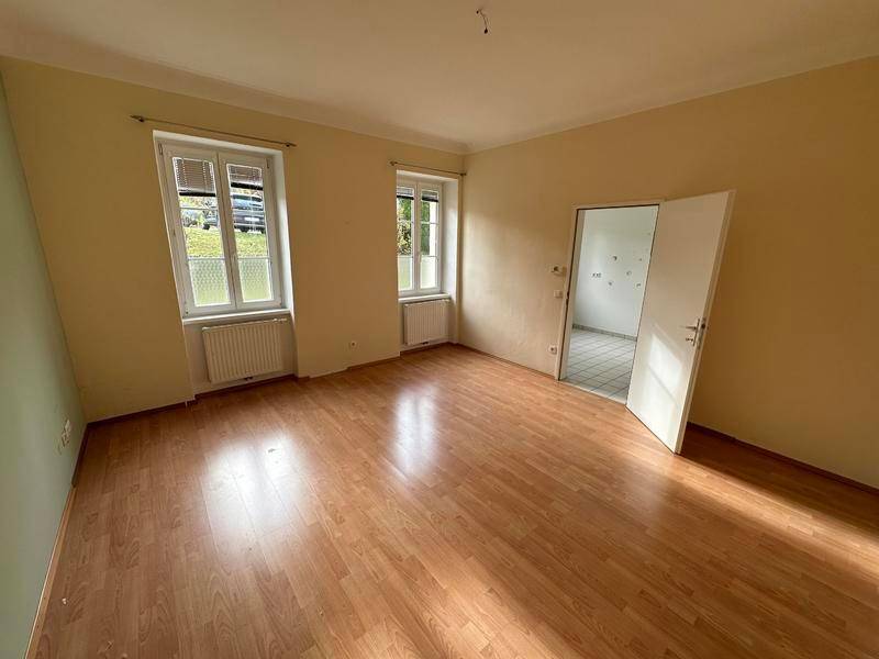 Leeres Zimmer mit Laminatboden und hellen Wänden, das vielseitig nutzbar ist.