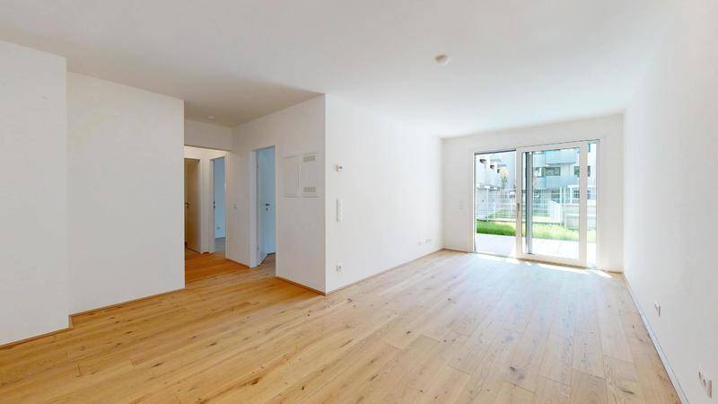 Helles Wohnzimmer mit Eichenparkettboden und großen Schiebetüren zum Garten.