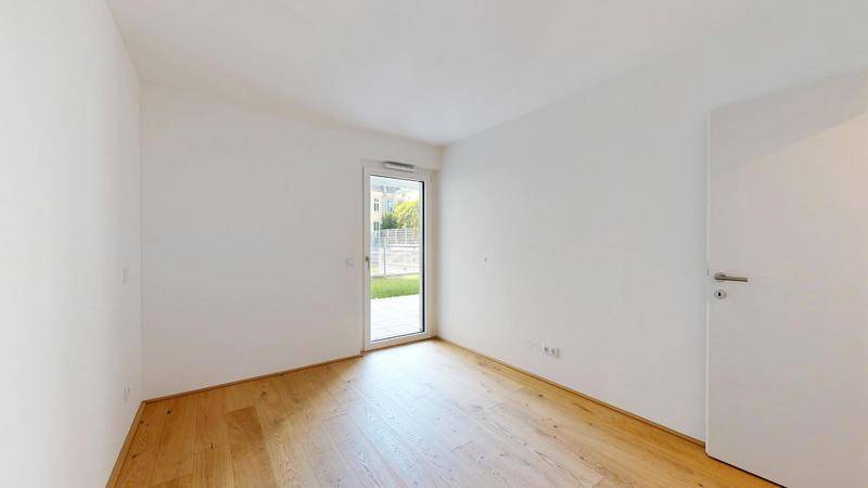 Geräumiges Schlafzimmer mit Parkettboden und direktem Zugang zum Gartenbereich.