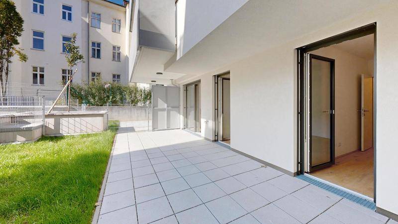 Geräumige Terrasse einer Erdgeschosswohnung mit direktem Zugang zum grünen Garten.