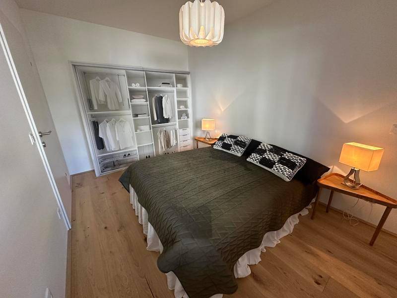Schlafzimmer mit großem Einbauschrank, Holzboden und modernen Nachttischen.