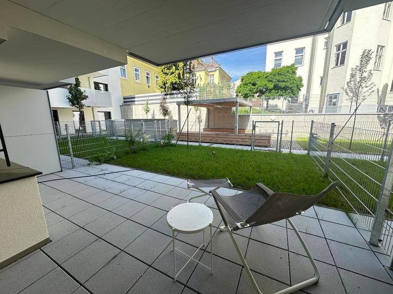 Gepflasterte Terrasse mit kleinem Rasenbereich und Blick auf die umliegenden Gebäude.
