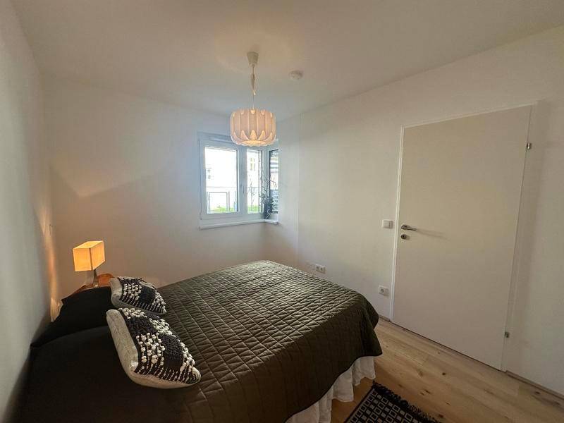 Gemütliches Schlafzimmer mit Holzboden, einem Fenster und indirekter Beleuchtung.
