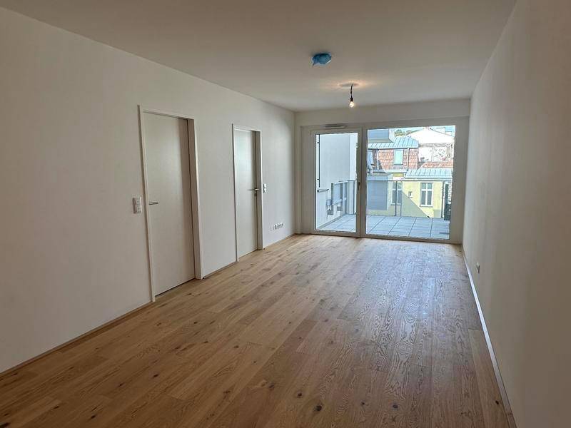 Heller Wohnraum mit Echtholzparkett und Zugang zu einem Balkon oder einer Terrasse.