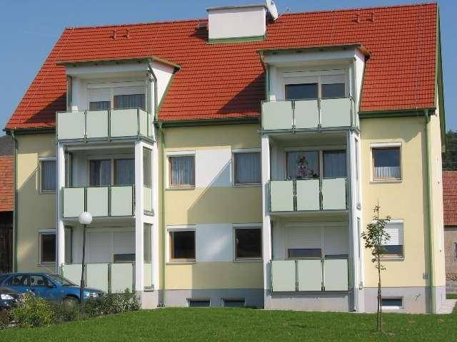 Mehrfamilienhaus mit gelber Fassade, rotem Ziegeldach und mehreren Balkonen.