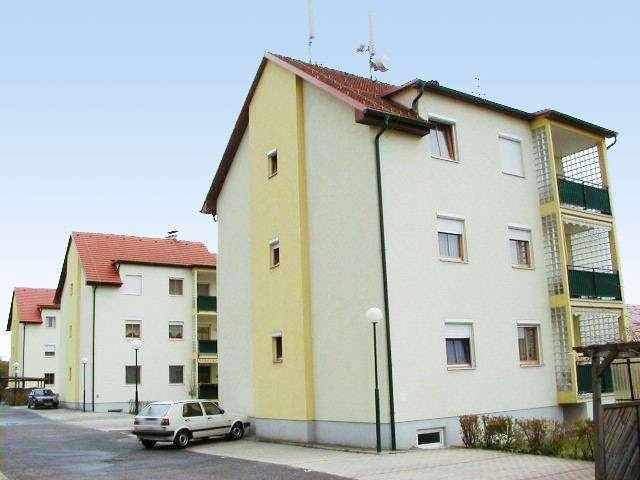 Mehrere Wohngebäude mit Satteldächern, Balkonen und Rollläden in einer ruhigen Wohngegend.