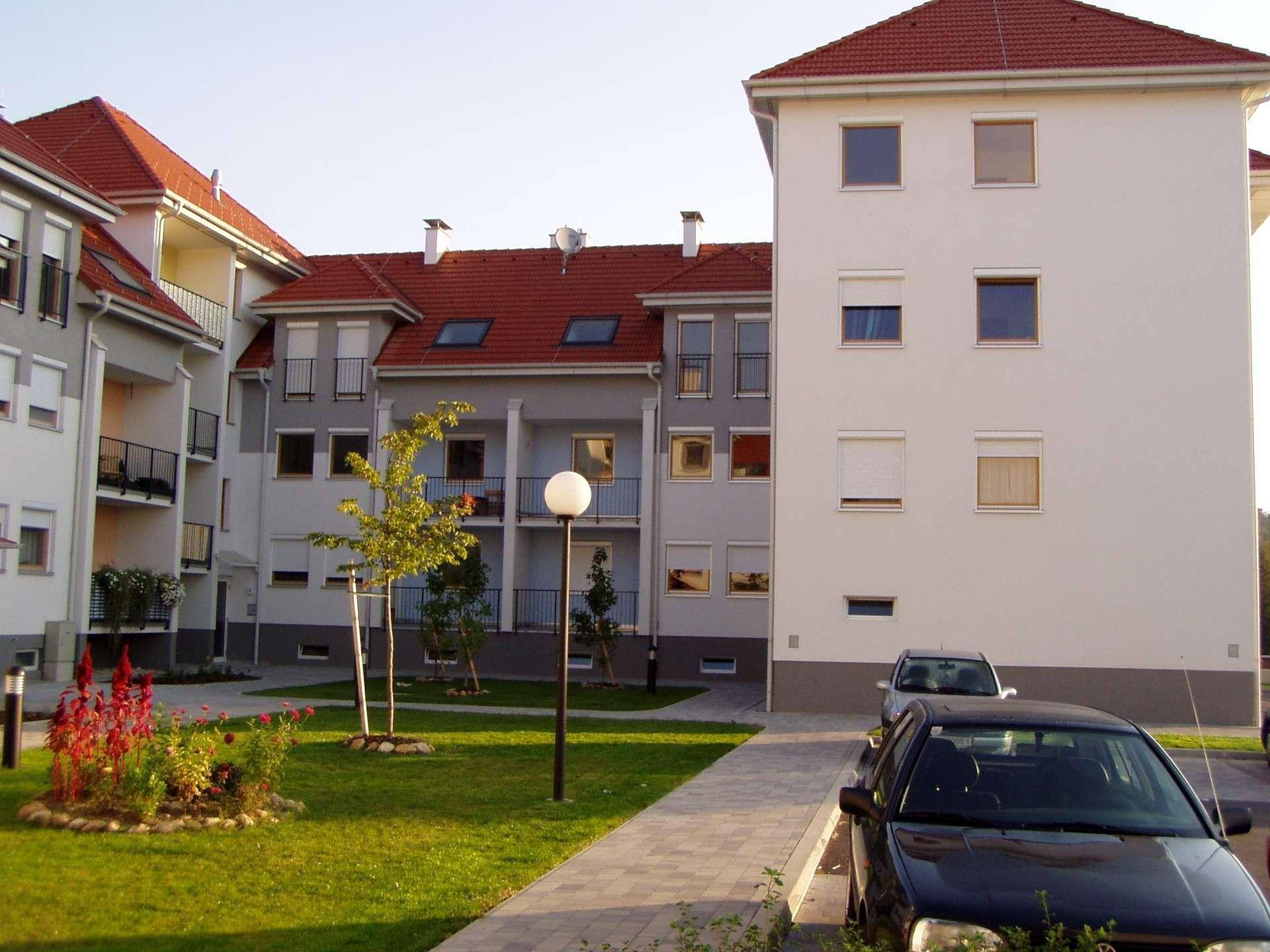 Blick auf die gepflegte Wohnanlage mit Innenhof, Grünflächen und parkenden Autos.