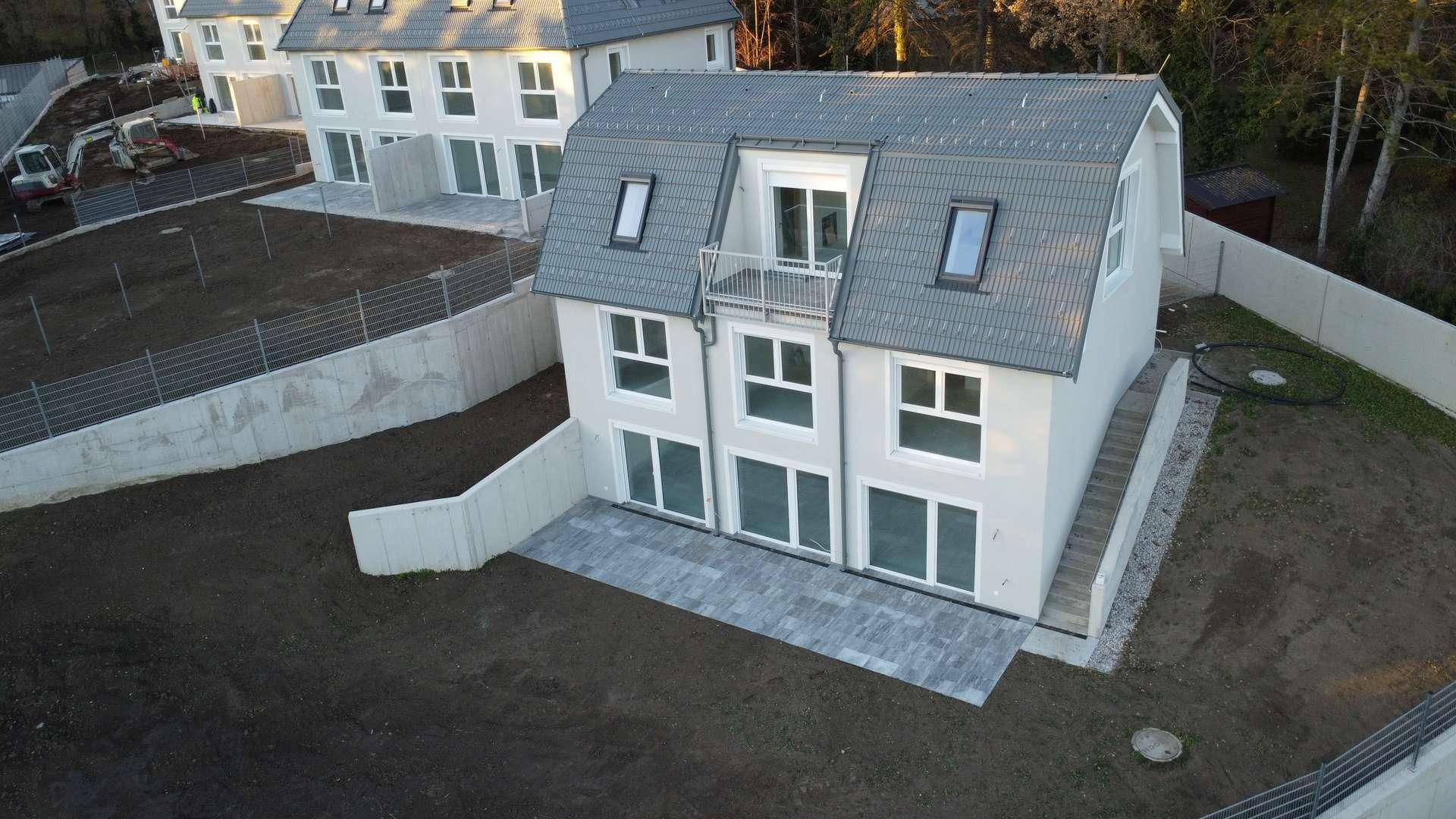 Neubau-Doppelhaushälfte mit gepflasterter Terrasse und vorbereitetem Gartenbereich.