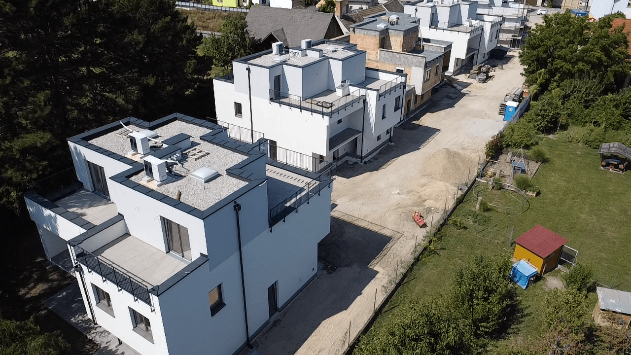 Luftaufnahme von modernen Reihenhäusern im Bau mit Flachdächern und Terrassenbereichen.
