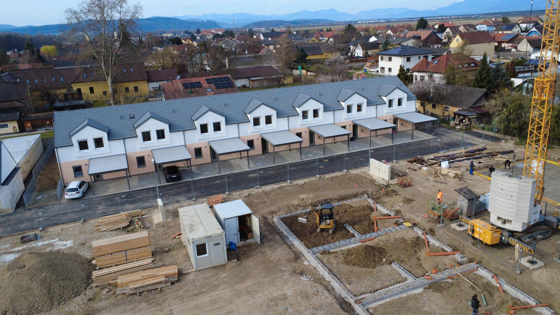 Weitläufige Luftaufnahme der Neubau-Reihenhäuser mit angrenzender Baustelle und Baukran.