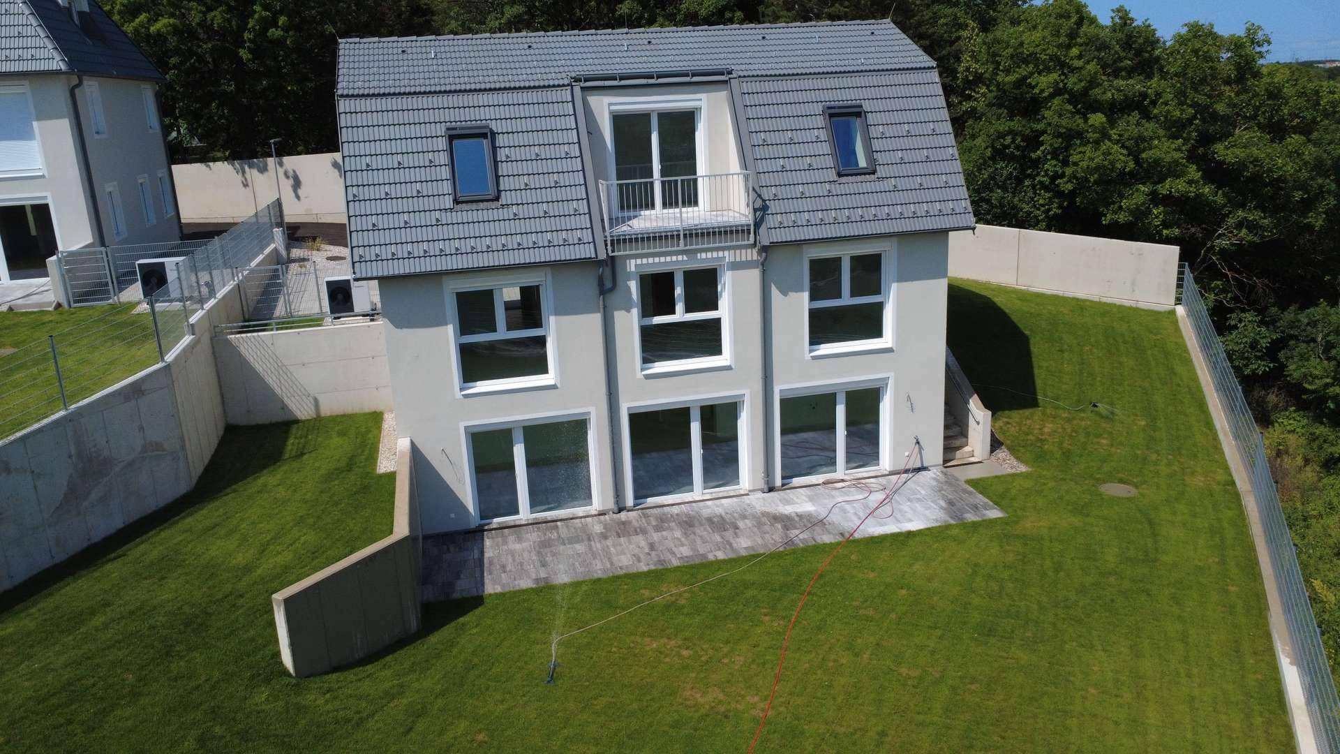 Moderne Doppelhaushälfte mit weitläufigem Garten und Blick auf die umliegende Natur.