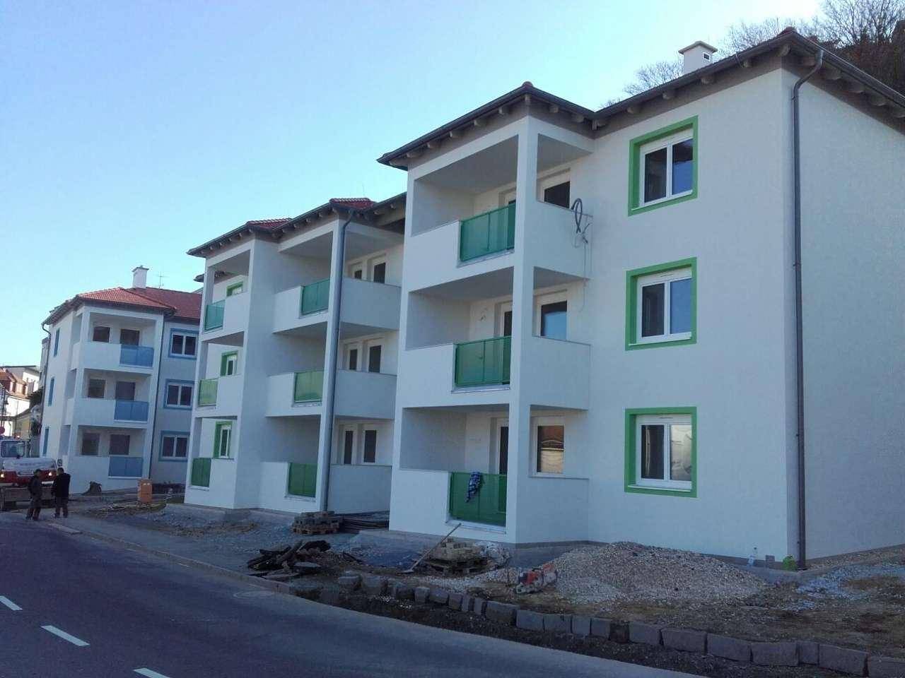 Neue Apartmentgebäude mit weißer Fassade und grünen Balkongeländern, noch im Bau befindlich.